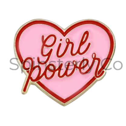 A heart-shaped enamel pin with a light pink background, red cursive 'Girl power' lettering, and a gold-toned metal border, shown on a white background with a faint watermark.