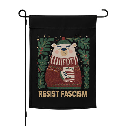 A black garden flag hanging from a black metal stand, featuring a cartoon polar bear wearing a red and white striped sweater with 'FDT' on the chest, surrounded by green leaves and the text 'RESIST FASCISM' at the bottom.