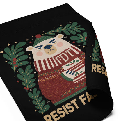 A black fabric product, likely a bandana or scarf, featuring a cartoon polar bear wearing a green beanie and a red-and-white striped scarf that reads 'FDT'. The bear is framed by green pine branches and has gold text reading 'RESIST FACISM'.